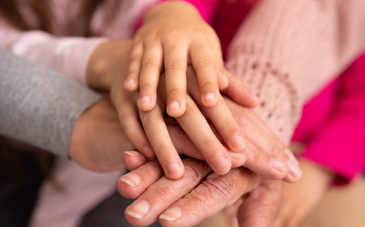 Grandmother's hands covered by younger generations' hands