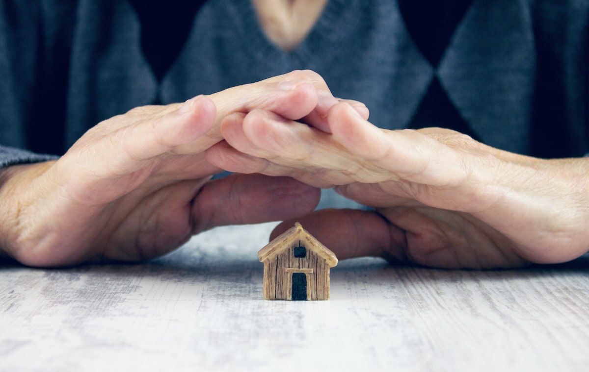 Person holding hands over small wooden house