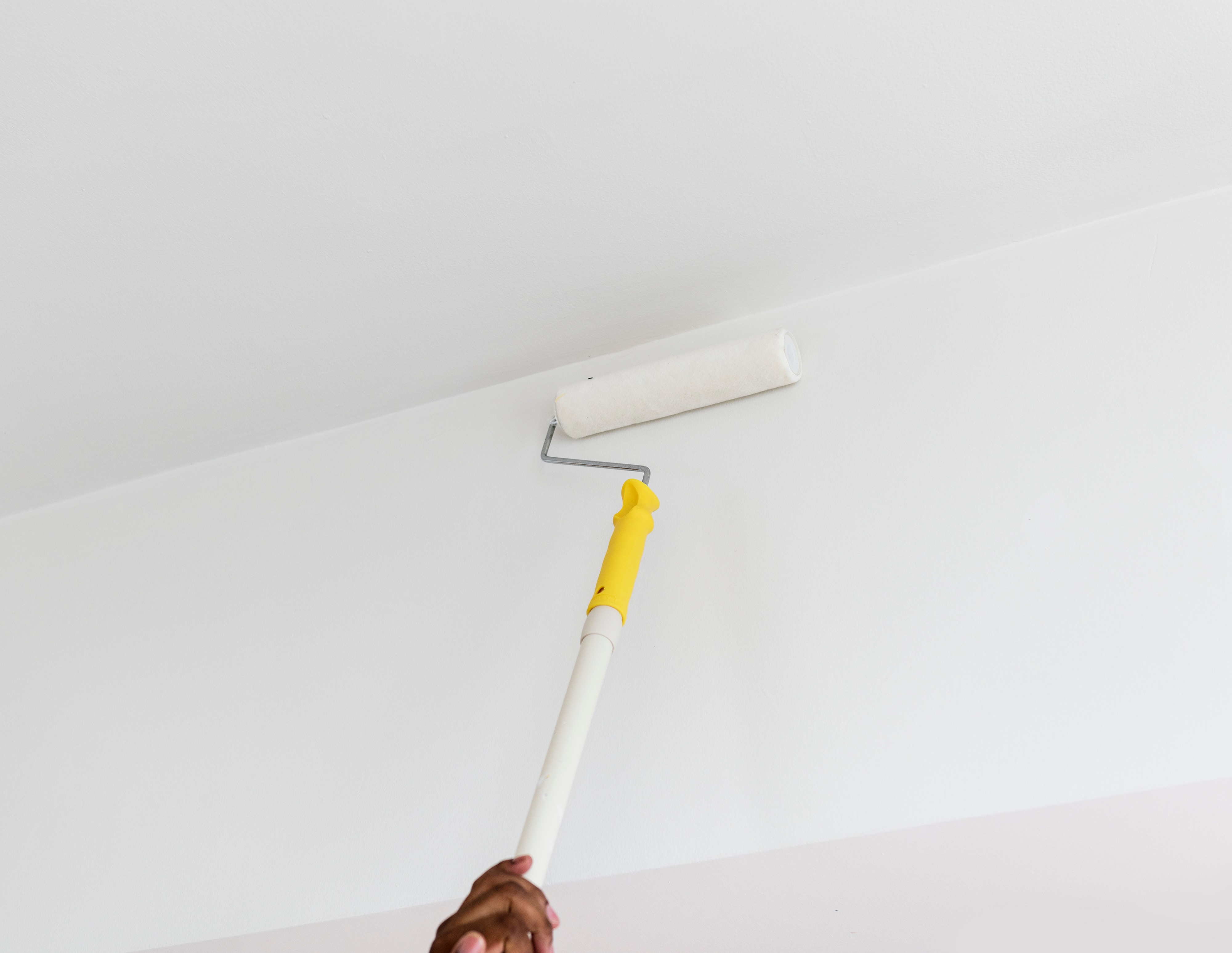 Person with ceiling paint roller