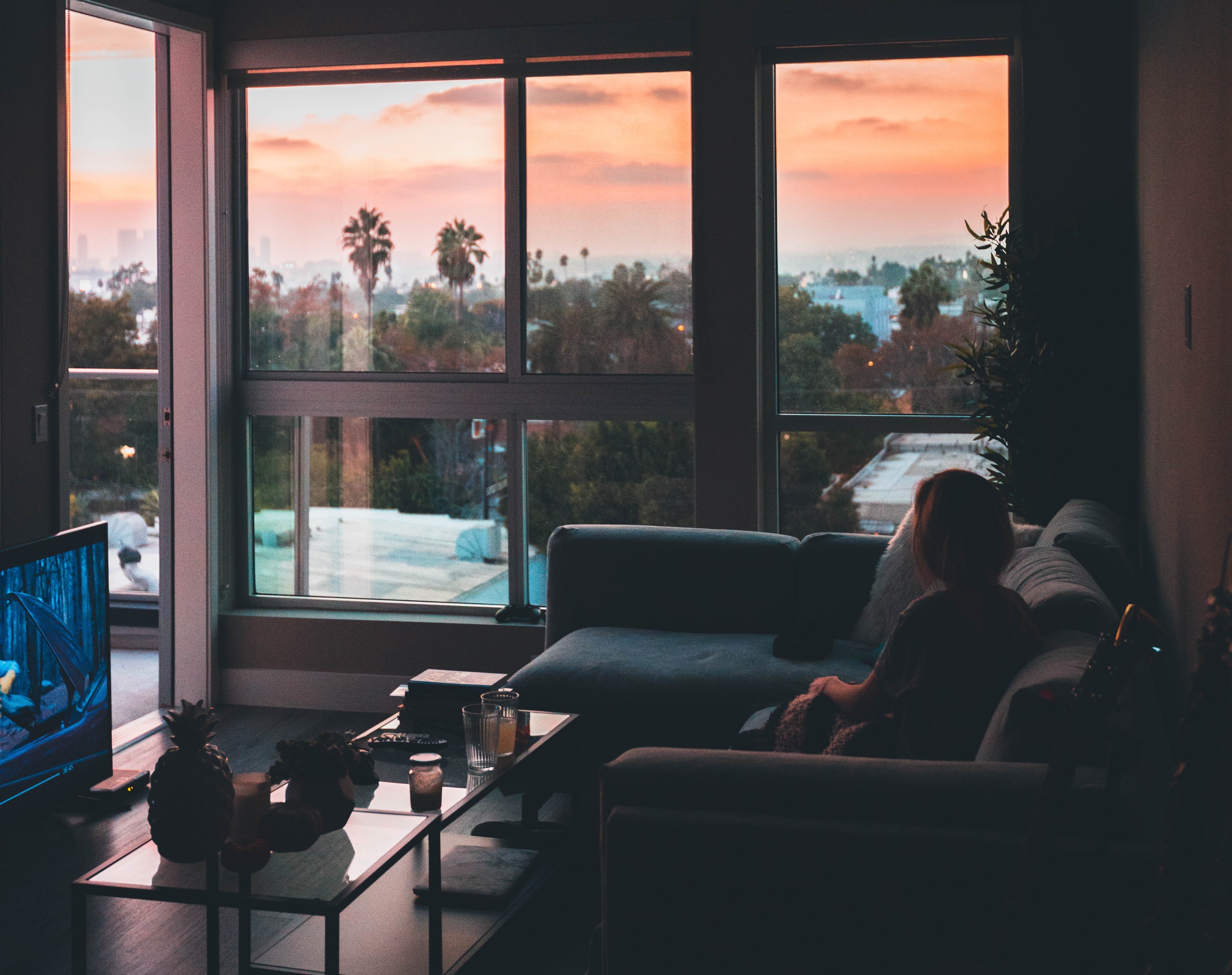 Woman sitting in living room during sunset