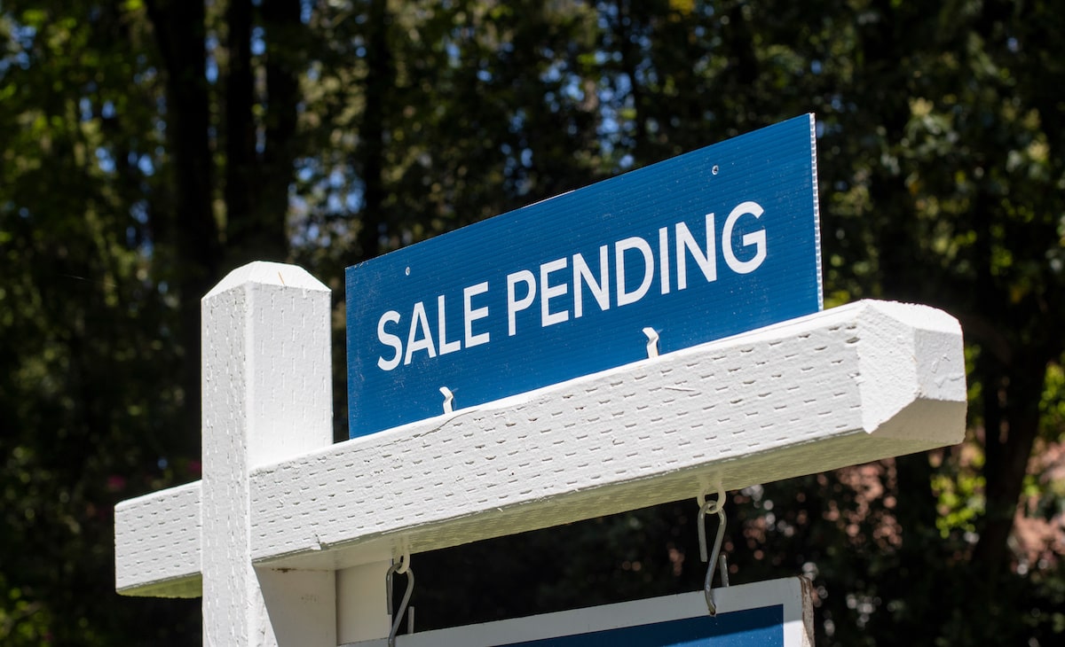 Blue sale pending sign above white for sale sign