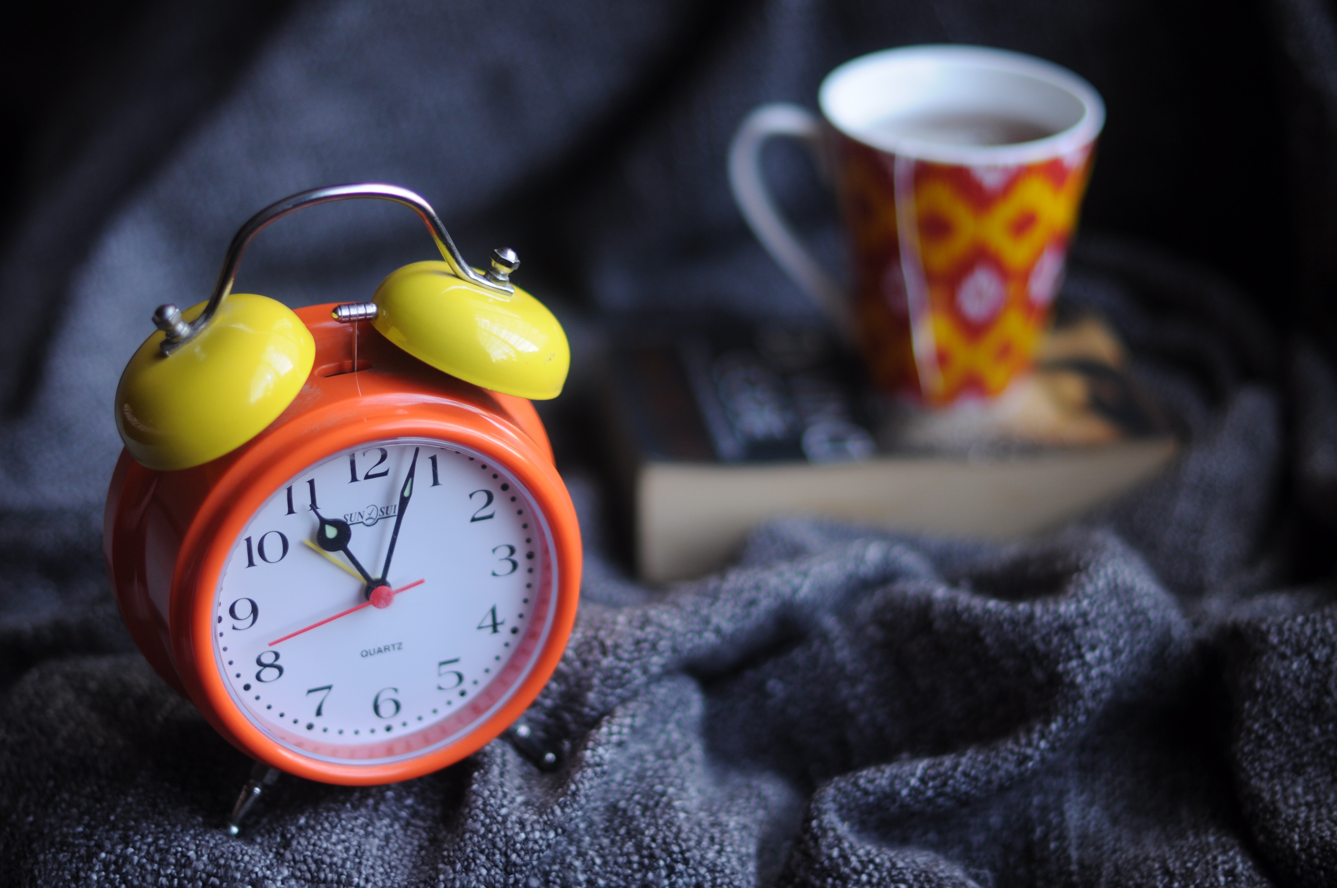 Clock and coffee mug on a bed