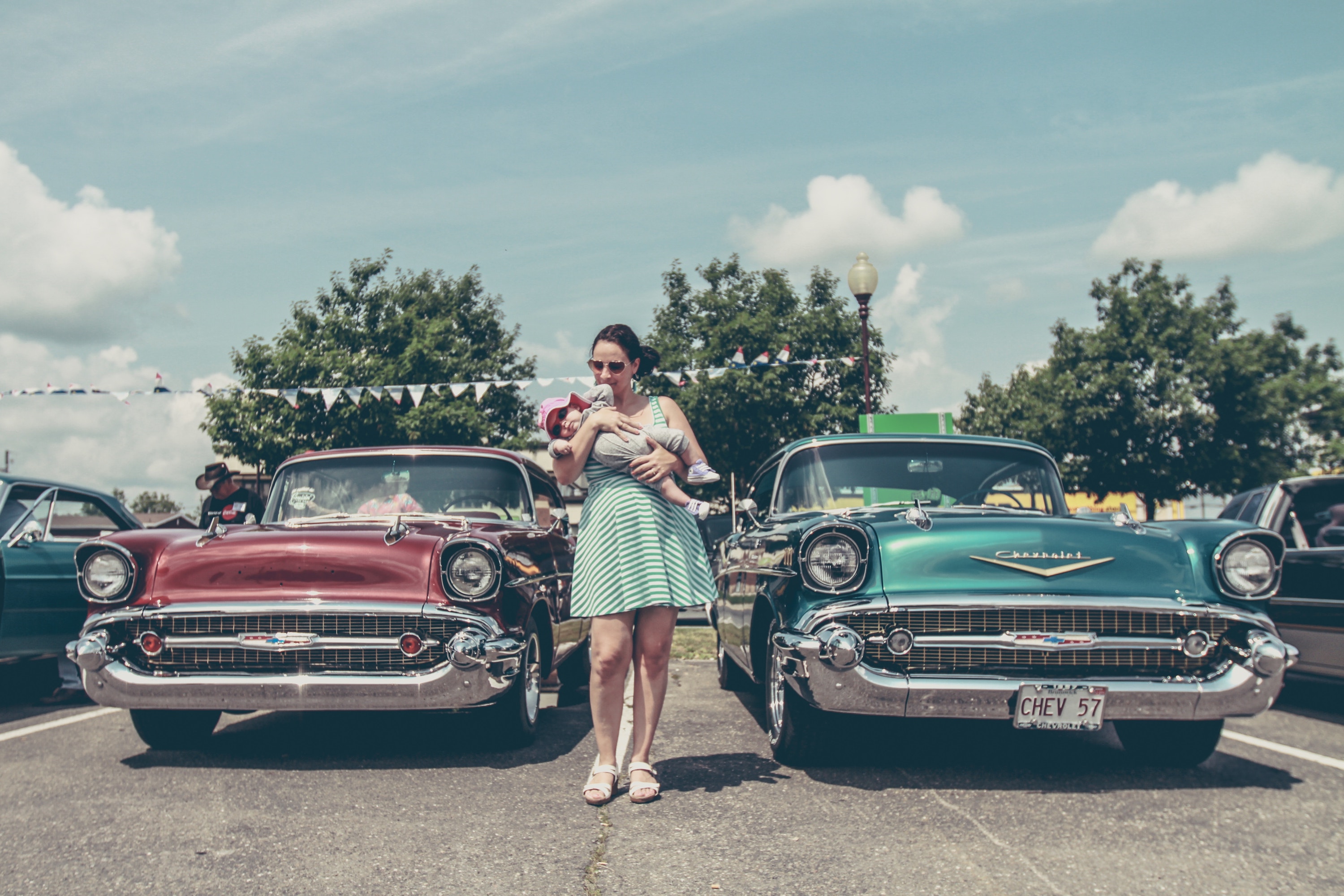 Woman with baby standing with vintage cars