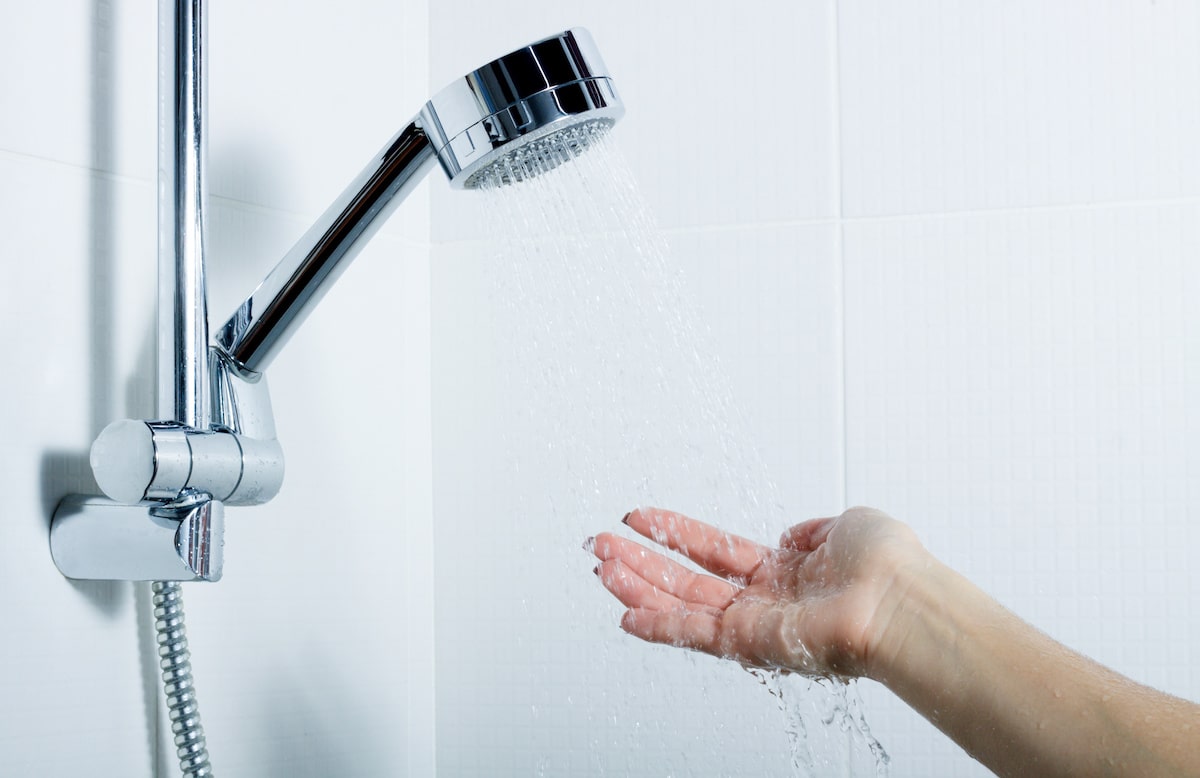 Hand under water flowing from showerhead