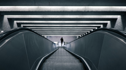 man riding long escalator down to subway