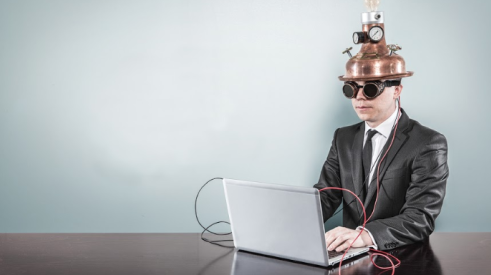 Man sitting with laptop and wearing a time machine helmet 