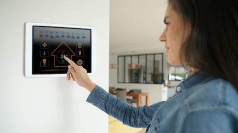 Woman using smart home touch screen on wall