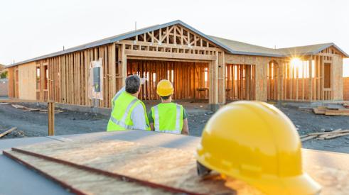 Two home builders looking at a house mid-construction