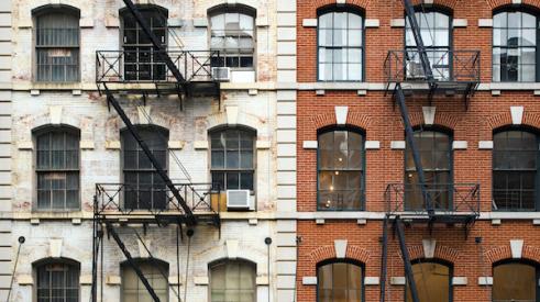 Exterior of two brick New York City apartment buildings with fire escapes