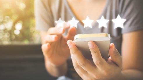 Woman using phone to leave 5 star rating