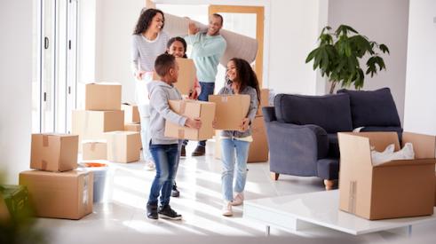 Family smiling while holding moving boxes