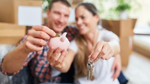 Homeowners smiling and putting coin into piggy bank