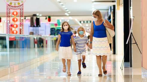 Mother and children wearing masks while walking through mall