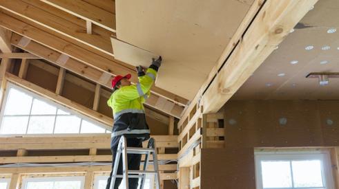 Home builder adding insulation to ceiling of home