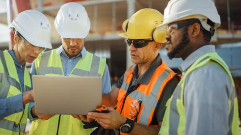 Group of home builders looking at a laptop screen on a jobsite