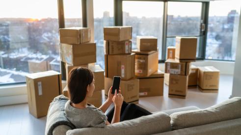 Woman sitting in city skyrise with moving boxes