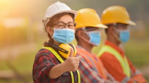 Construction employees wearing masks, one gives a thumbs up