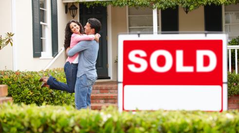 Smiling couple with sold house