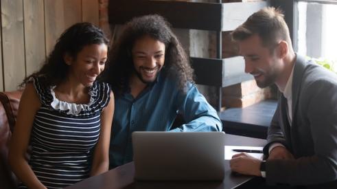 Couple and realtor smiling at laptop