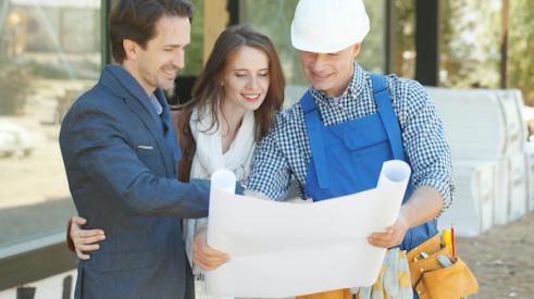 Builder smiling and showing plans to smiling clients