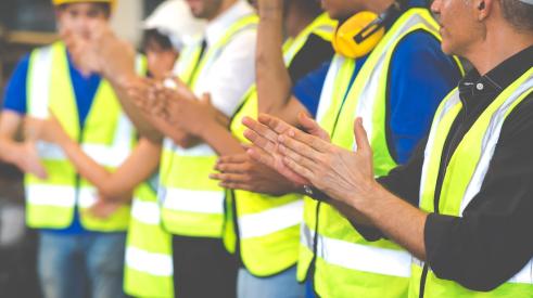This photo shows a row of construction workers clapping.