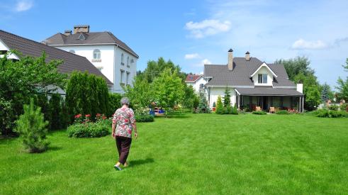 Older homebuyer walks through yard to small home