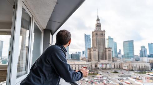 Man in apartment looks at city skyline