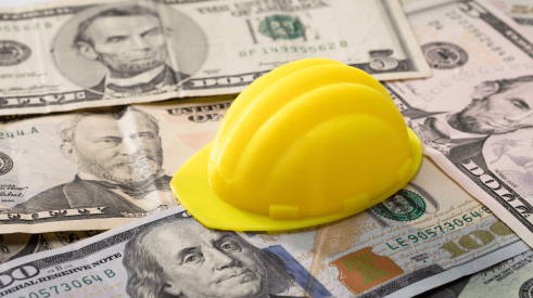 Construction spending with yellow hardhat on US currency