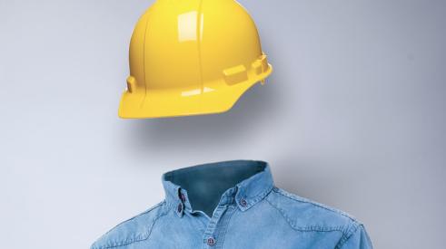 Yellow hard hat hovering above blue button-down shirt with no construction worker visible