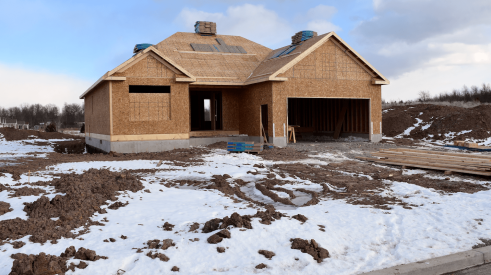 Home under construction in cold climate with snow on the ground