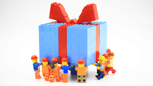 Lego construction workers carry holiday gift