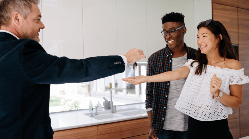 Salesman handing over keys after selling a new-construction home to a young couple