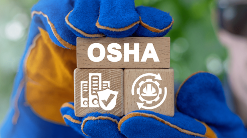Gloved hands holding wooden blocks with OSHA and other construction site safety symbols