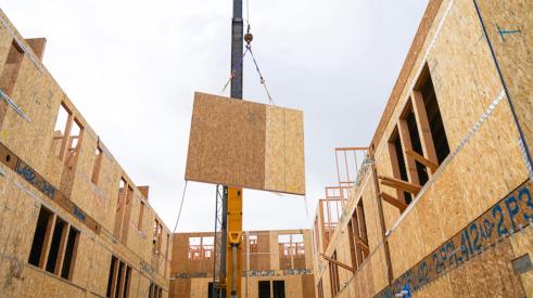 Crane hoisting a wall prefab panel