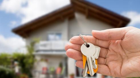 New homebuyer holds keys in front of house