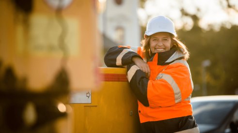 Smiling woman construction worker wearing white hardhat on jobsite