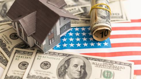 House model surrounded by cash on top of American flag cut out