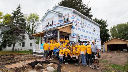 Vikings team next to Habitat for Humanity house in West St. Paul