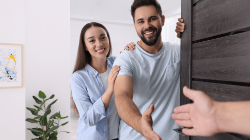 Young couple of renters welcoming as they open the door to their apartment