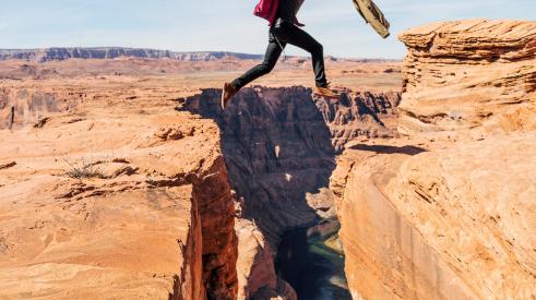 Man jumping over gap between cliffs