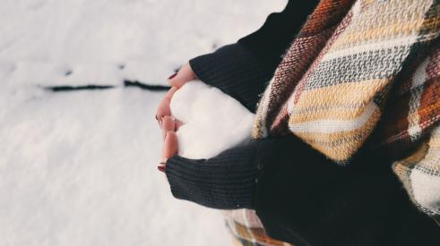Person holding heart-shaped snowball