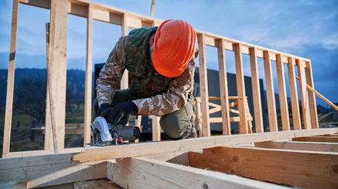 Builder using circular saw to cut timber framing for building a new home