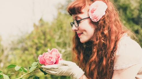 Woman smelling a rose in her garden enjoying the outdoors