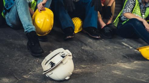 White hard hat on ground next to group of construction workers sitting down