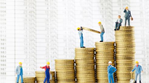 Small construction worker figurines stacking coins