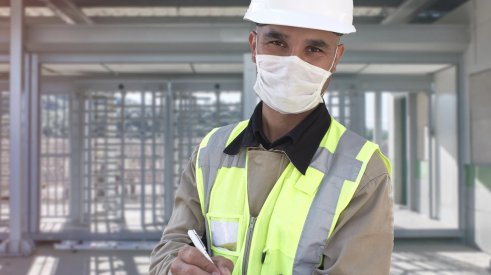 Happy construction worker on jobsite wearing protective facemask