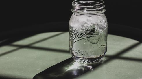 Mason jar with ice water in it on table