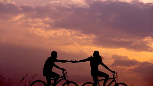 Couple riding bikes, holding hands