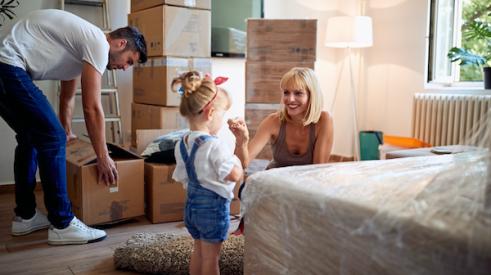 young family packing boxes in bedroom in preparation for moving house