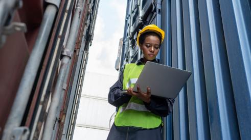 Women wearing construction gear and looking at laptop on job site